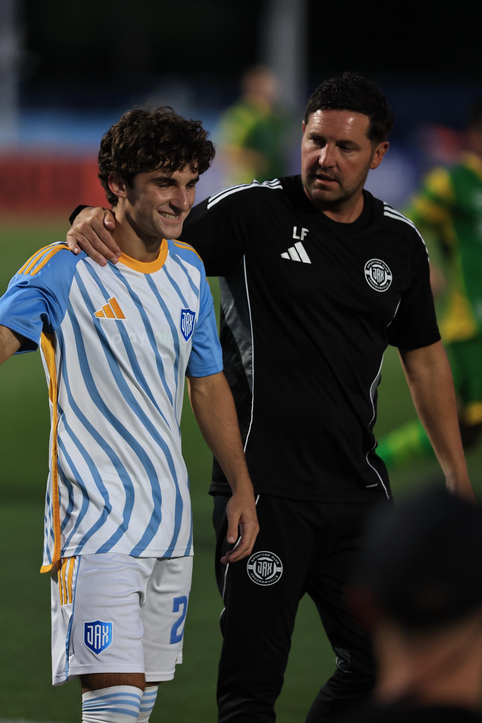 Sporting JAX midfielder Ethan Underwood receives words of encouragement from head coach Liam Fox while entering the match.
